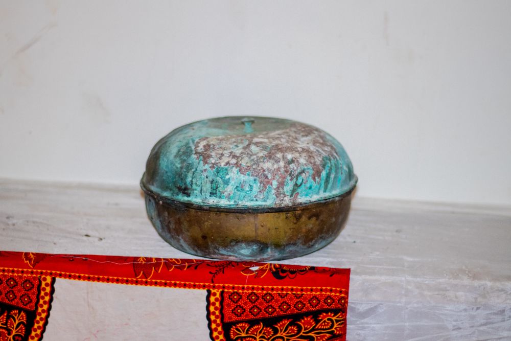 A brass covered bowl with green verdigris on the lid