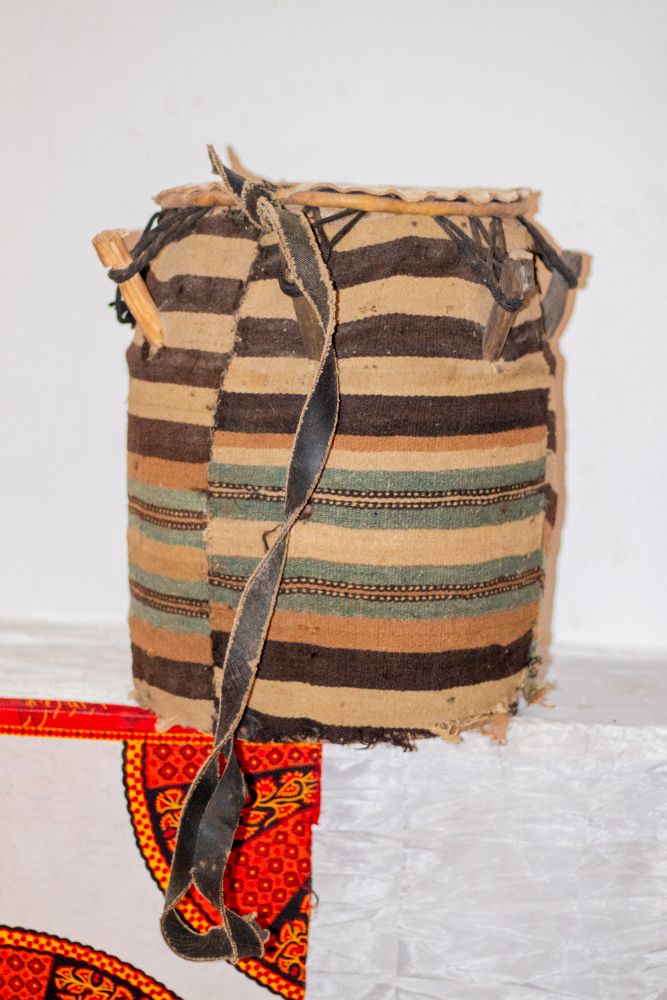 A drum wrapped in brown and green strip-woven cloth