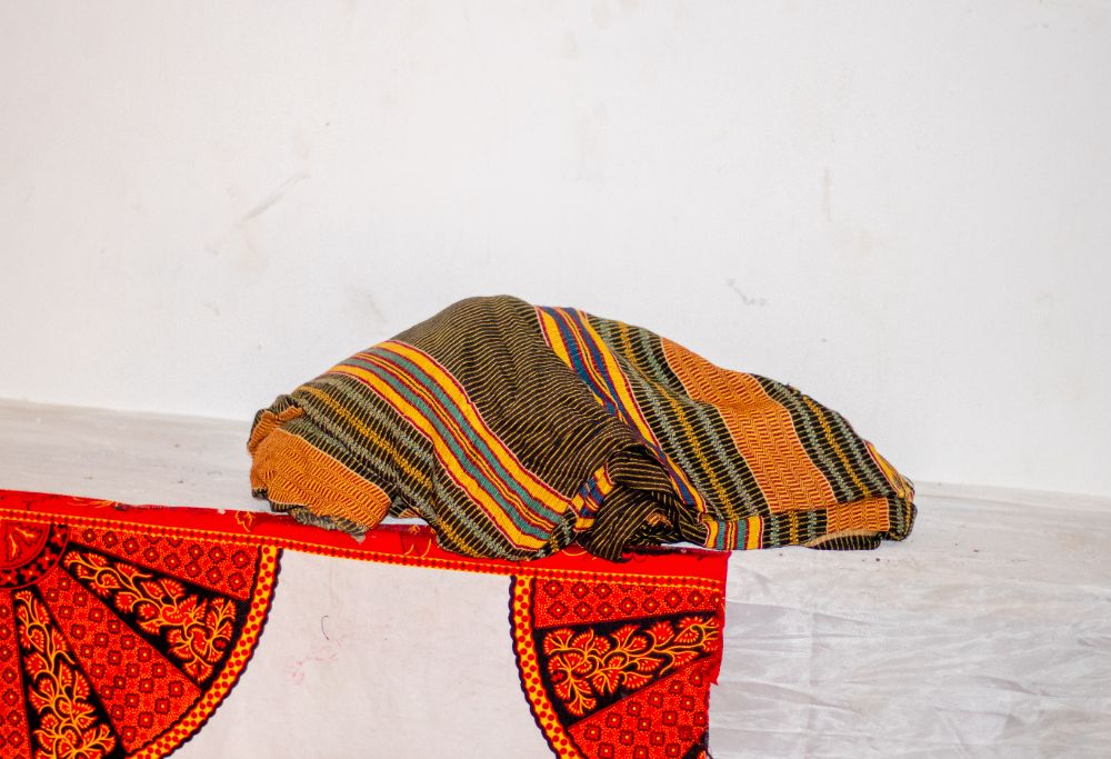 Folded kente cloth in gold, black and green stripes