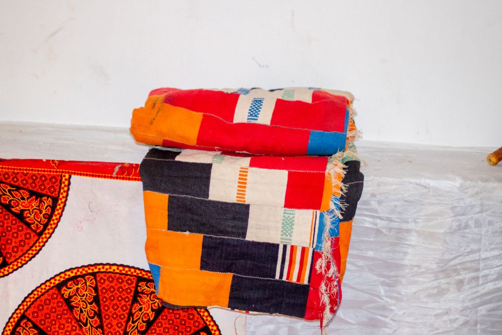 Folded kente cloths in orange, red, indigo and white blocks