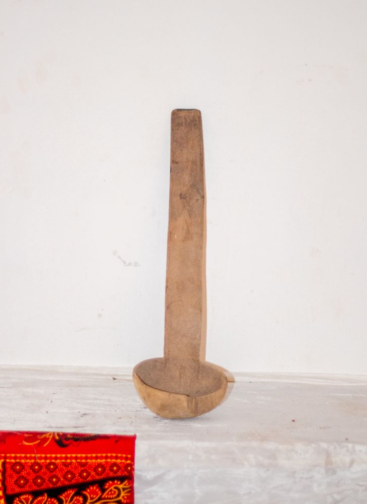 A carved wooden ladle standing upright