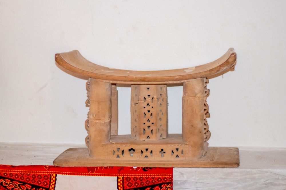 A carved stool with a pierced decorative centre panel