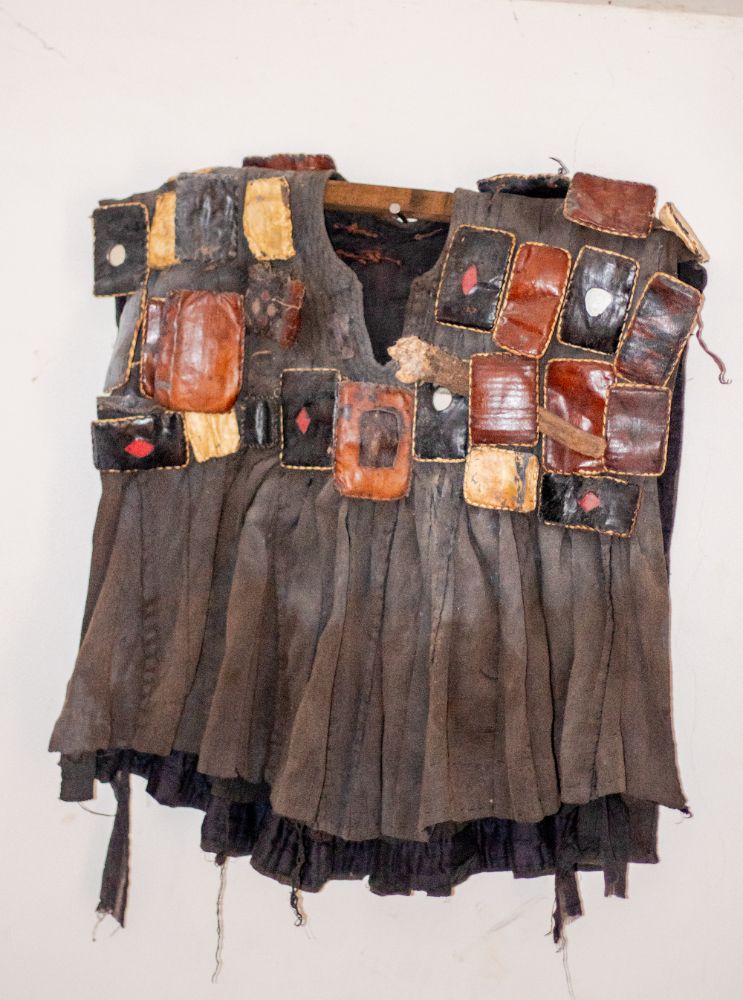 A dark war smock covered in leather amulet packets