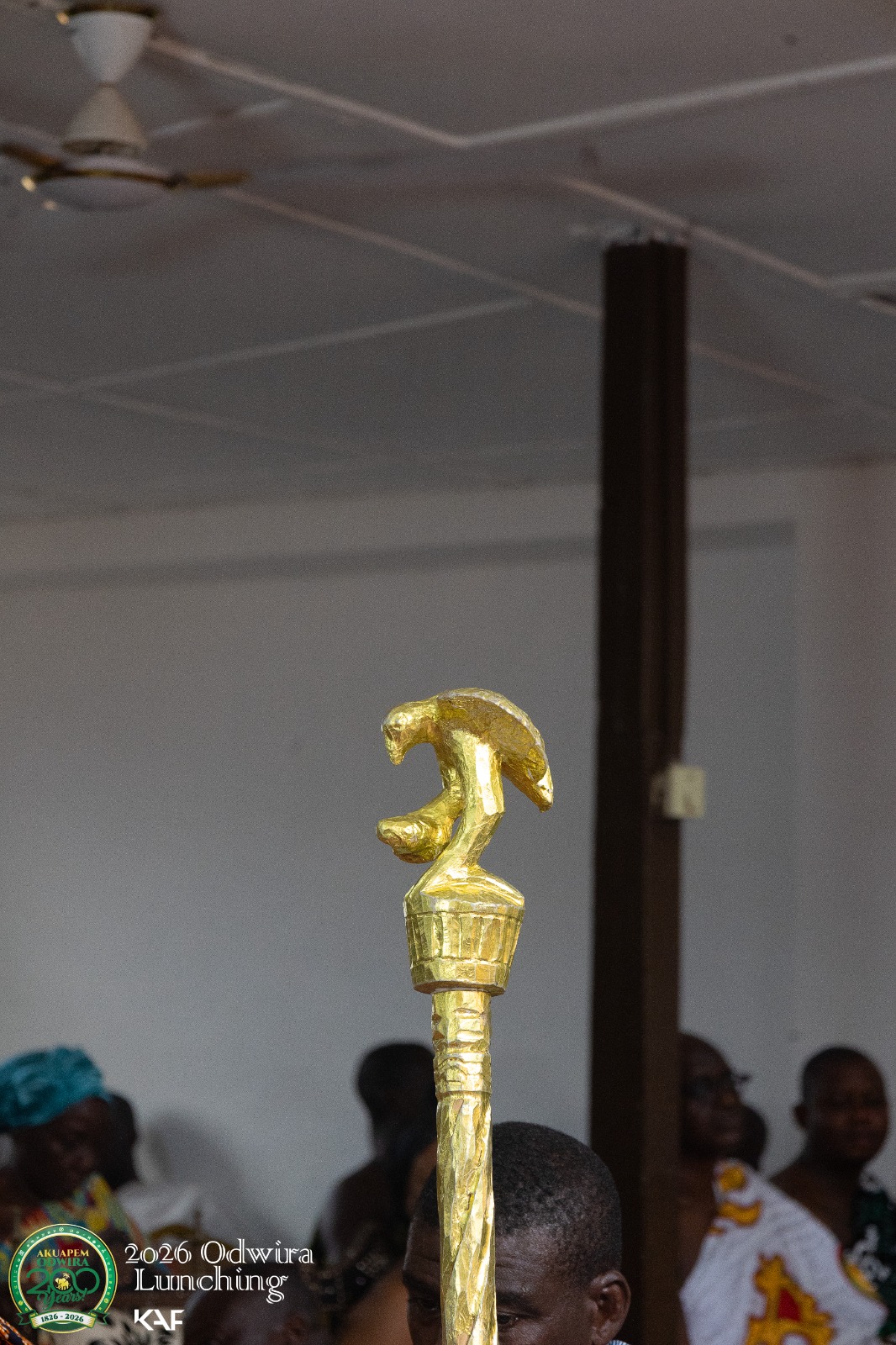 A gold bird finial standing over a rounded form on a linguist staff