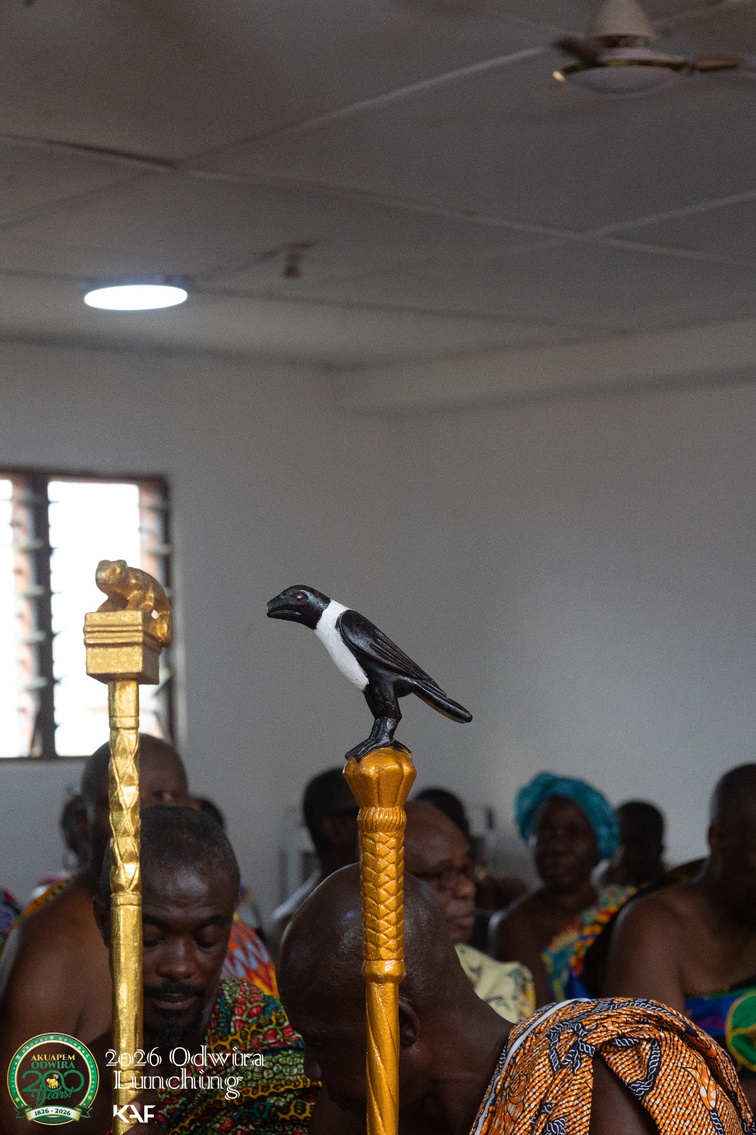 A carved pied crow finial in black and white on a gold linguist staff